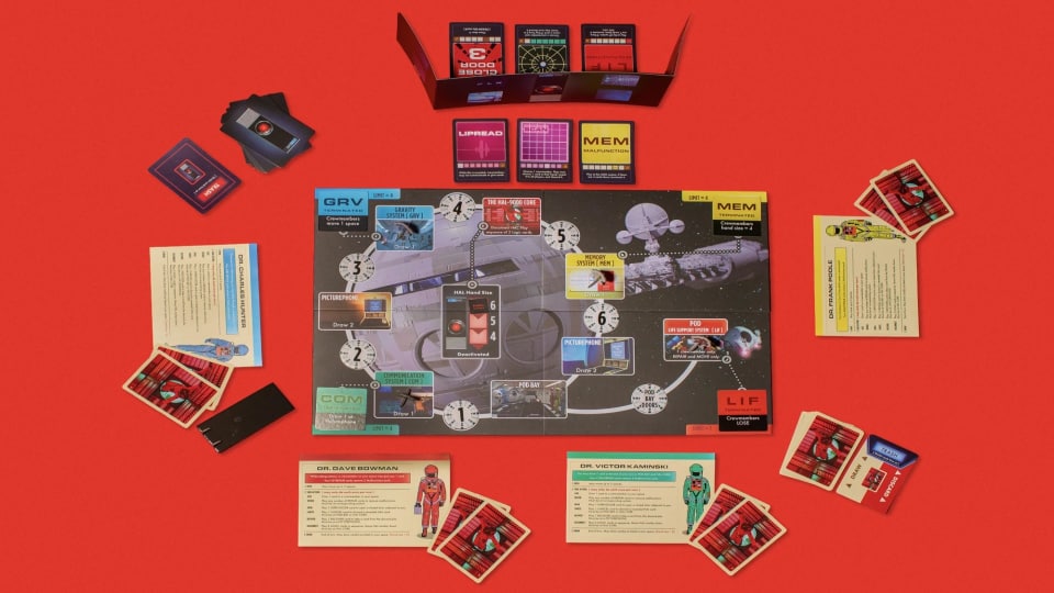 A board game with cards and cut outs on a red background.