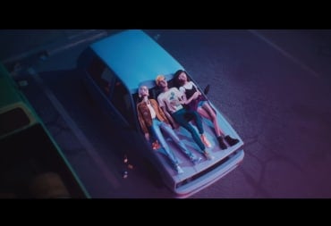 Three teenagers laying on the hood of a car.