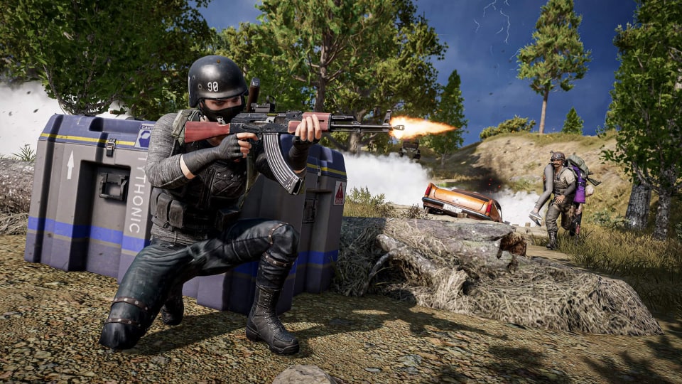 A player firing a gun while another carries a third player in the background in PUBG